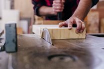 Manos de carpintero recortadas trozo de madera en el taller - foto de stock