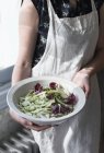 Midsection of woman in apron holding bowl of fresh mixed salad. — Stock Photo
