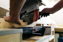 Crop carpenter hand cutting piece of wood with mechanic saw — Stock Photo