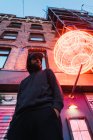Von unten: Mann posiert unter Neon-Kreis auf Straße — Stockfoto