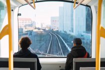 Back view of two unrecognizable men riding on city train. — Stock Photo