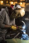 Retrato del trabajador en tubo de soldadura de máscara en el taller - foto de stock