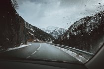 View to snowy hills and empty asphalt road from car. — Stock Photo
