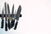 Cintre magnétique avec assortiment de couteaux de cuisine sur mur blanc . — Photo de stock
