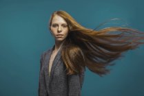 Porträt einer rothaarigen Frau mit wehendem Haar auf blauem Hintergrund — Stockfoto