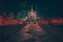 Perspective view to ornate historic gate and bridge on street at night. — Stock Photo