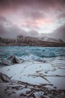 Vista della superficie del ghiacciaio del gelo con sfondo di scogliere rocciose in nuvole cupe . — Foto stock