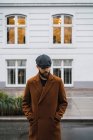 Portrait of bearded man in vintage coat and cap looking down at street scene — Stock Photo
