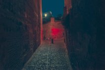 View to empty dark alley with red illumination at night. — Stock Photo