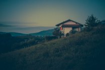 Vista alla grande casa sul pendio della collina erbosa al tramonto della sera . — Foto stock