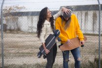 Two girl with longboards fooling at street scene — Stock Photo