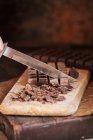 Messer schneidet Schokoladentafel auf Holzbrett — Stockfoto