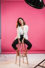 Sorridente donna bruna seduta su uno sgabello in studio — Foto stock