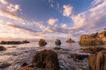 Rocky costa oceanica sotto nuvoloso paesaggio luminoso in cielo — Foto stock