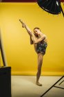Bailarina de ballet sosteniendo pierna levantada sobre fondo amarillo - foto de stock