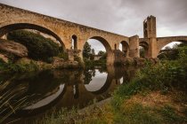 Exterior view of medieval bridge reflecting in river — Stock Photo