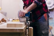 Mittelteil des Tischlers poliert Stück Holz in Werkstatt — Stockfoto