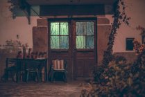 Exterior of facade with table and chairs by wooden door with light in building — Stock Photo