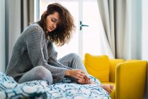 Молодая сонная женщина сидит на кровати — стоковое фото