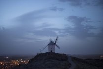 Vista para o moinho de vento histórico na colina sob o céu nublado no crepúsculo . — Fotografia de Stock