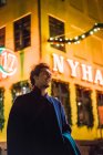 Fröhlicher Mann im Mantel auf beleuchteter Nachtstraße — Stockfoto