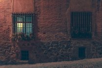 Exterior view to windows with greed in building on street at night. — Stock Photo