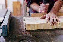Manos de carpintero de los cultivos corte pieza de madera en el banco de trabajo - foto de stock