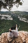 Вид ззаду пари, що сидить на скелі і захоплюючий пейзаж — стокове фото