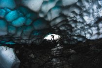 Silhouette of person posing in end of ice cave with textured beautiful ceiling. — Stock Photo