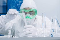 Scientifique fournissant une expérience de chimie avec des flacons en laboratoire . — Photo de stock