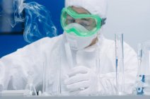Scientist making experiment with steaming flasks — Stock Photo