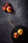 Натюрморт зі свіжих персиків на темному столі . — стокове фото