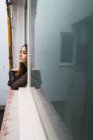 Молодая девушка смотрит в окно на открытом воздухе — стоковое фото