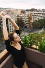 Young girl in glasses outstretching arms on terrace — Stock Photo