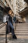 Jovem mulher de casaco casual posando na escada na rua . — Fotografia de Stock