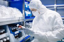 Cientista que trabalha olhando para garrafa em armazenamento de laboratório — Fotografia de Stock