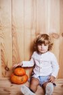 Charming kid Sitting on floor by stacked pumpkins — Stock Photo