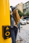 Jovem mulher de chapéu e traje de ganga olhando pensativo enquanto caminha na rua . — Fotografia de Stock