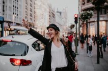 Fröhliche Frau nimmt Taxi in Stadtstraße — Stockfoto