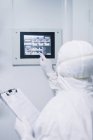 Rear view of scientist operating with display on wall — Stock Photo