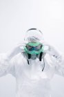 Ученый в белой форме надевает защитную маску — стоковое фото