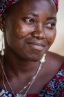 BENIN, ÁFRICA - 31 de AGOSTO de 2017: Retrato de mulher negra sorridente com roupas étnicas desviando o olhar . — Fotografia de Stock