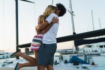 Молода любляча пара обіймається на пірсі з яхтами на фоні . — стокове фото