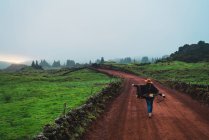 Vue arrière de la femme marchant sur la route rurale — Photo de stock
