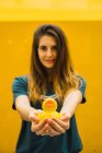 Charming woman outstretching hands with rubber duck on background of yellow wall — Stock Photo