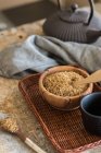 Tigela com açúcar mascavo na bandeja de vime e xícara de chá e toalha — Fotografia de Stock