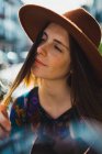 Чуттєва молода жінка в капелюсі грає з волоссям — стокове фото