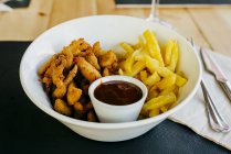 Жареные куриные палочки с картошкой фри и соусом на тарелке — стоковое фото