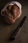 Freshly baked bread and knife on dark background — Stock Photo