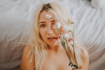 Mulher sensual com rosas deitadas na cama — Fotografia de Stock